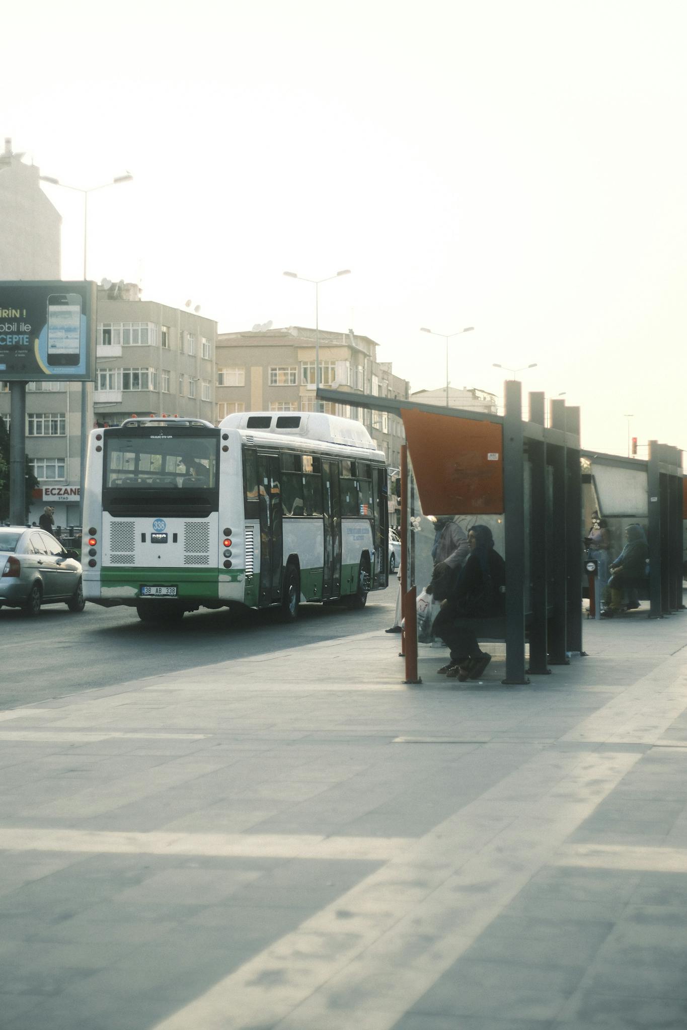 A bustling urban bus stop during sunset, showcasing public transportation and city life.